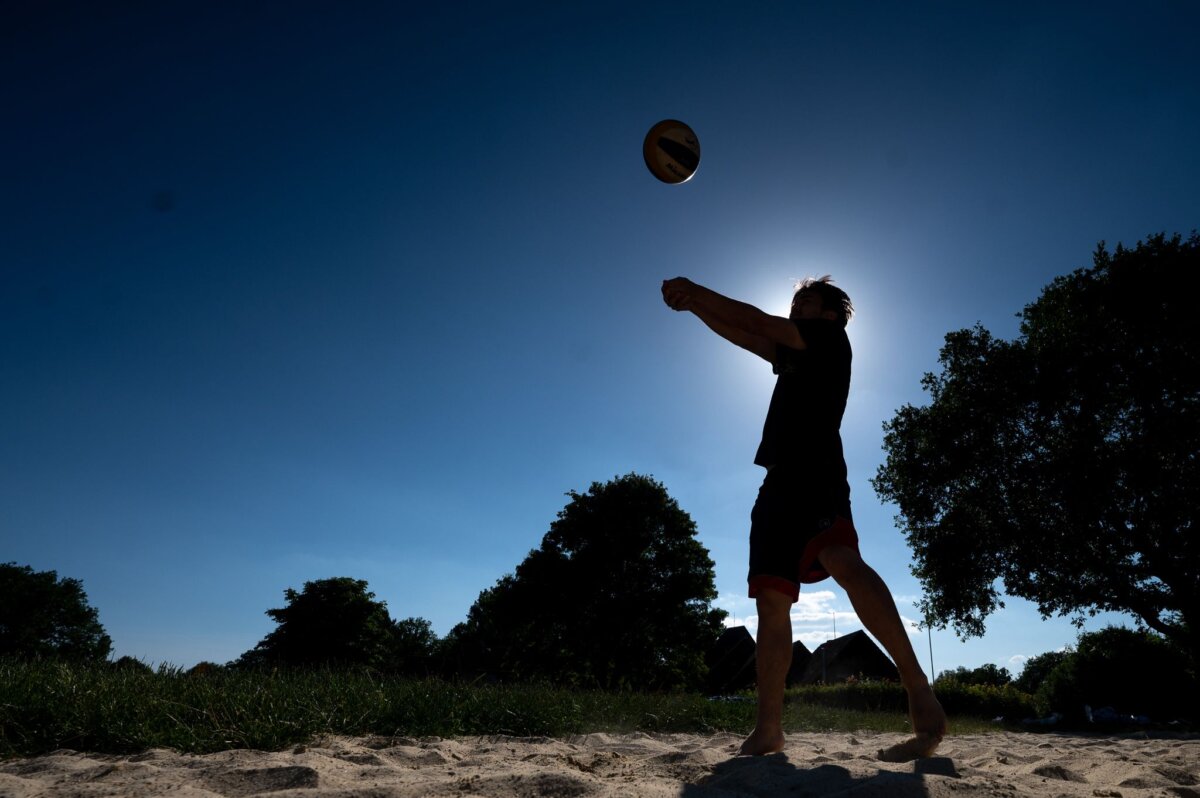 Ein Mann baggert am Buga-See in Kassel auf einem Beachvolleyballfeld einen Volleyball.